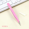 A pink precision crafting tool with a pointed tip rests on a light surface next to a white pencil and a keyboard.