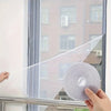 A hand holds an invisible anti-mosquito window screen sheet against a window pane.