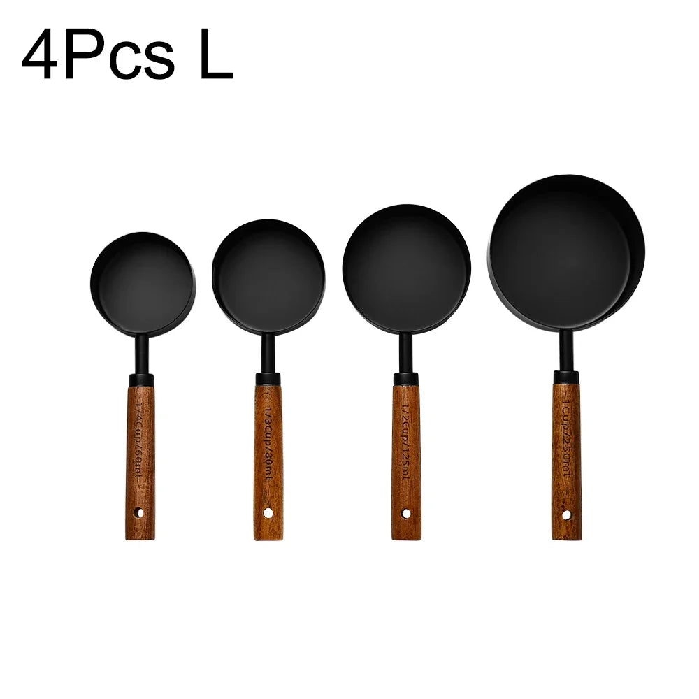 A set of four black measuring spoons with wooden handles.