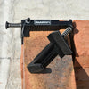 A black precision wire clip tool with a spring mechanism is shown resting on a brick surface.