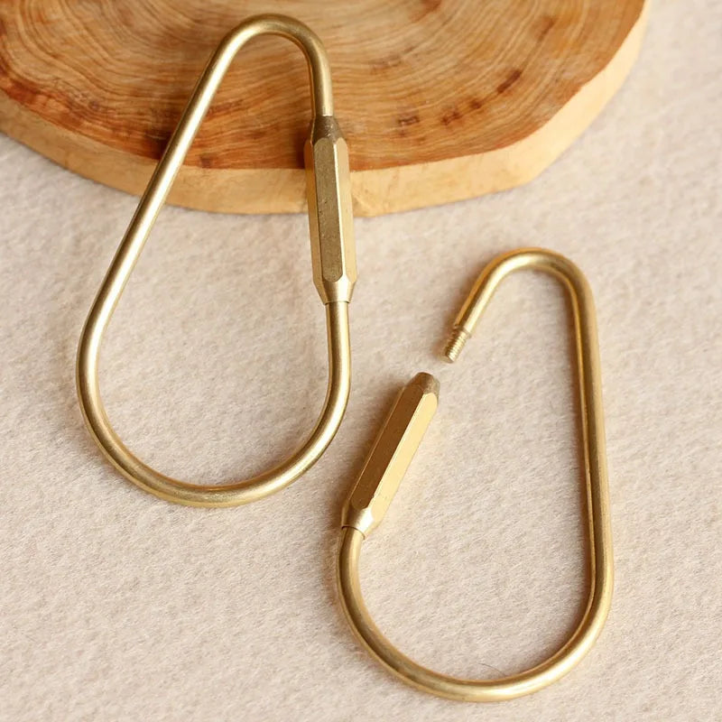 Ein Paar Messing-Gold-Schlüsselring-Karabinerclips auf einer hellen Oberfläche.