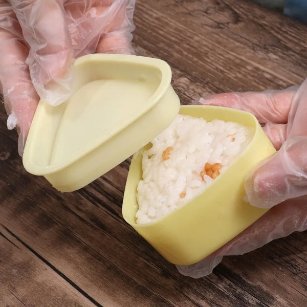 Hände in Handschuhen halten einen gelben Plastikbehälter mit weißem Reis für ein DIY Sushi- und Onigiri-Set