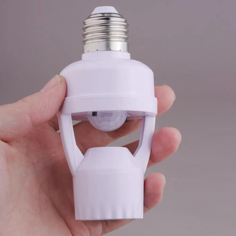 A hand holds a white PIR motion sensor light bulb adapter with a screw-in base and a clear lens.