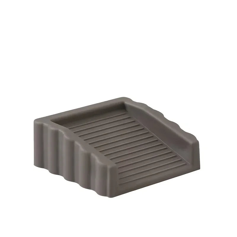 A gray reusable TPR door stop wedge with ribbed texture.