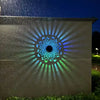Sonniges Mandala-Außenwandleuchte wirft bei Nacht ein helles, strahlendes Muster auf eine Wand.