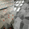 A professional tile leveling and spacing kit is shown on a gray tiled floor, with various tools and tiles visible.