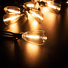 A close-up shot of a glowing light bulb attached to a wire, illuminating a dark surface with warm light.