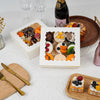 A white box of decorative cookies and a small square card featuring various baked goods and fruit
