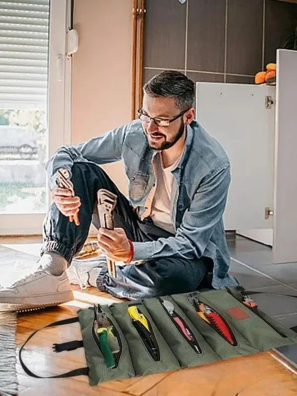Ein Mann organisiert ein Set tragbarer Multitools in einer grünen Tasche auf einem Holztable.