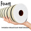 A hand holds a roll of imitation wood grain wall stickers, showing the texture and white wrapping.