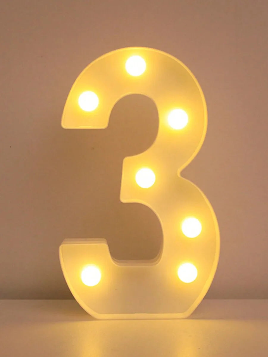 Una luz nocturna de letra y número LED brillante con forma de tres, iluminando la superficie inferior.