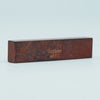 A rectangular piece of reddish-brown wood with the name Guyker and number 4560 engraved on it.