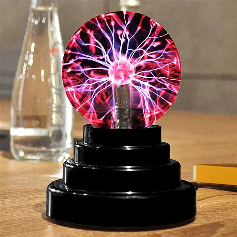 A glowing magenta and purple plasma ball LED night light resting on a black stand.