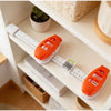 An orange precision picture hanging level and angle measuring tool is displayed on a white shelf.