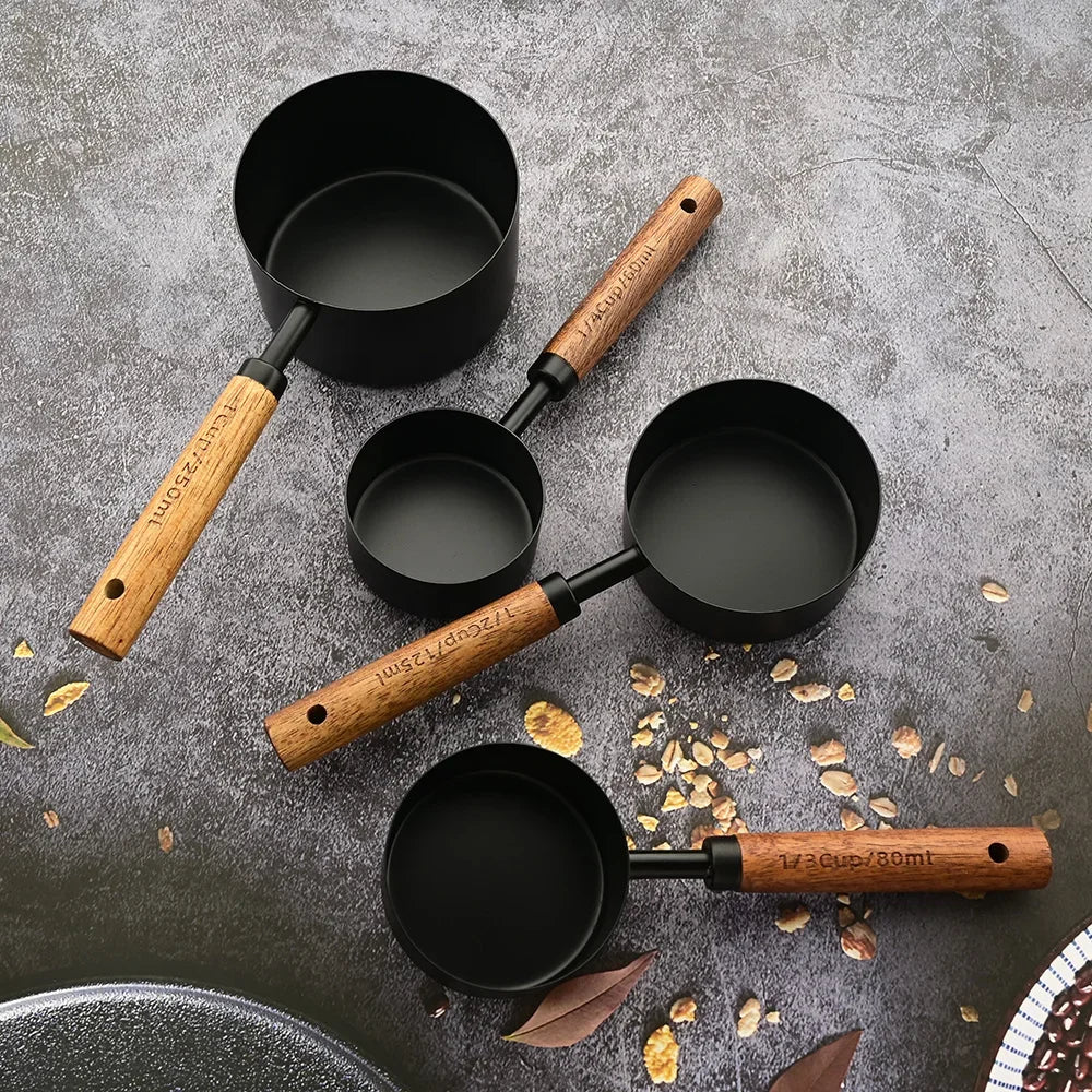 A set of stainless steel and wooden measuring spoons scattered on a gray surface.