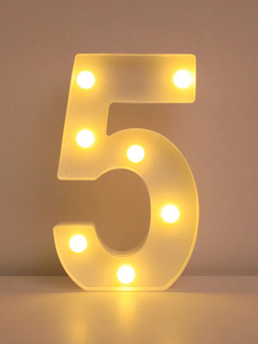 Una luz nocturna de letra y número LED brillante con forma de cinco, iluminando la superficie inferior.