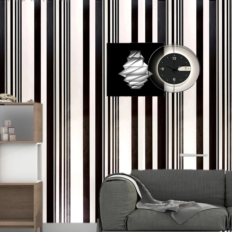 A close-up of a wall decorated with vertical black and white striped vinyl strips, featuring a round clock display.