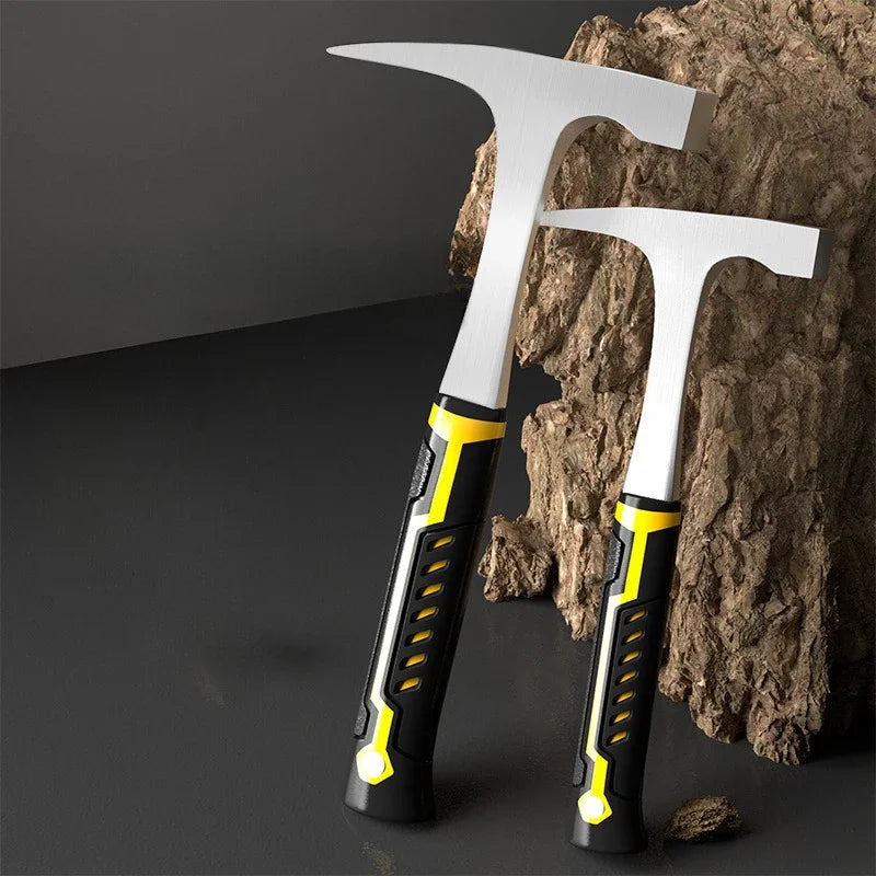A silver and black forged geological rock pick hammer resting on a dark surface next to a rough rock.