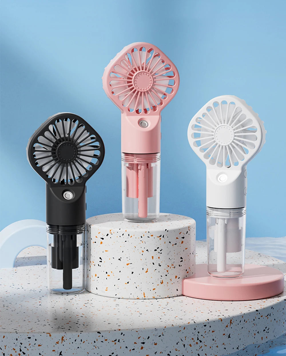 A collection of pink and white portable USB rechargeable mist fans displayed on a light surface.