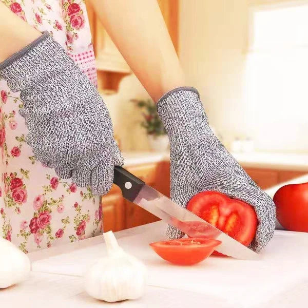 Eine Hand mit grauen Schutzhandschuhen bereitet frische Zutaten wie Knoblauch und Tomaten vor.