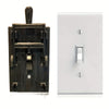 A black decorative flip handle light switch cover mounted on a white electrical plate.
