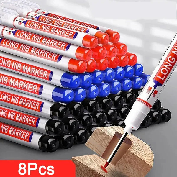 A collection of red and white long nib marker pens with black tips arranged in a pile on a wooden block.