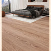 Schlafzimmeransicht mit Holzbettrahmen, dunkler Bettwäsche und hellem Teppich auf Holzoptikboden.
