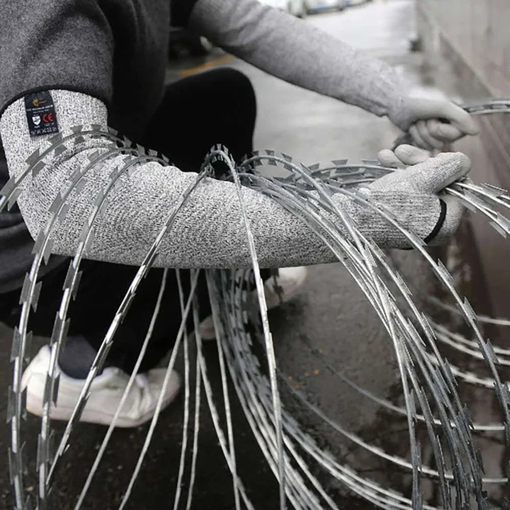 A person wearing gray arm sleeves is handling a bundle of silver wire for protection.