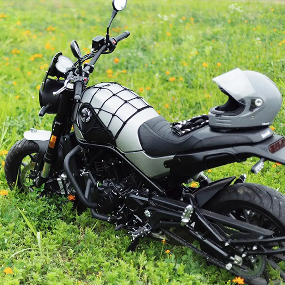 Schwarzes und silbernes Motorrad mit strapazierfähigem Gepäcknetz-Organizer auf einer Wiese.