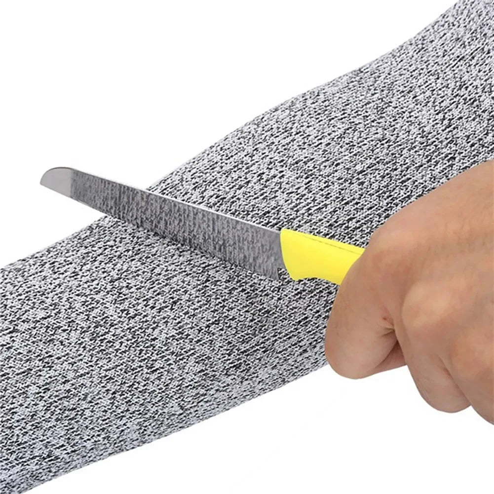A hand holds a knife inserted into a gray and black textured arm sleeve for protection.