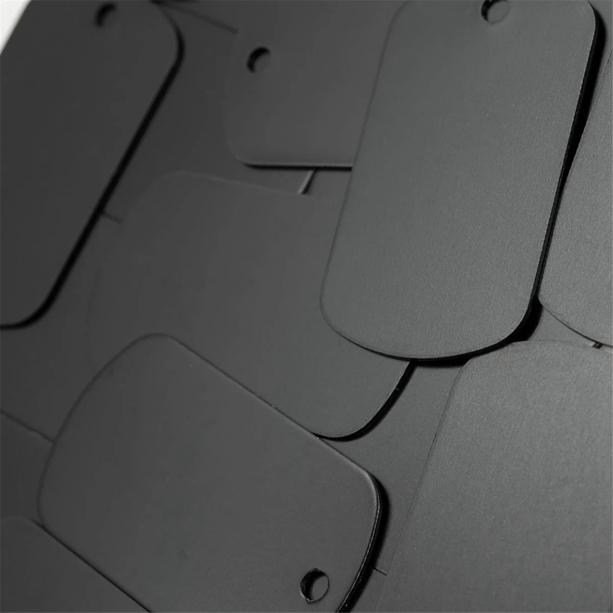 A close-up view of 50 aluminum metal stamping tags for crafts and keychains in black.