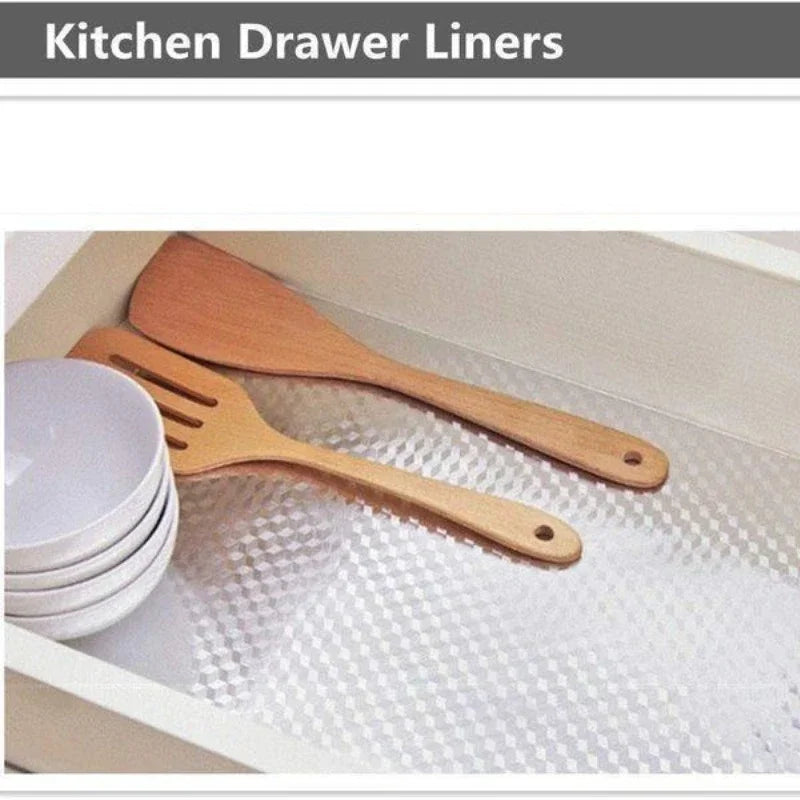Ustensiles de cuisine en bois et assiettes blanches sont montrés à l'intérieur d'un revêtement de tiroir.