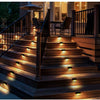 Exterior view of wooden stairs illuminated by ground-level solar LED lights leading to a deck and outdoor seating area.