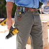 A person wearing denim shirt and jeans is holding a yellow cordless drill tool attached to a leather belt hook and holster.