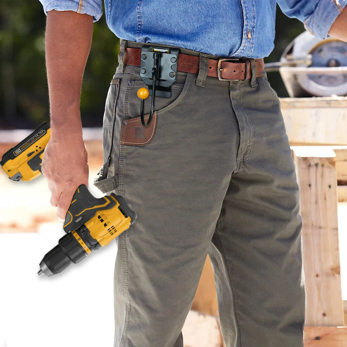 A person wearing denim shirt and jeans is holding a yellow cordless drill tool attached to a leather belt hook and holster.
