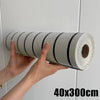 A hand is holding a roll of self-adhesive wood grain wall panels, showing the texture and size.
