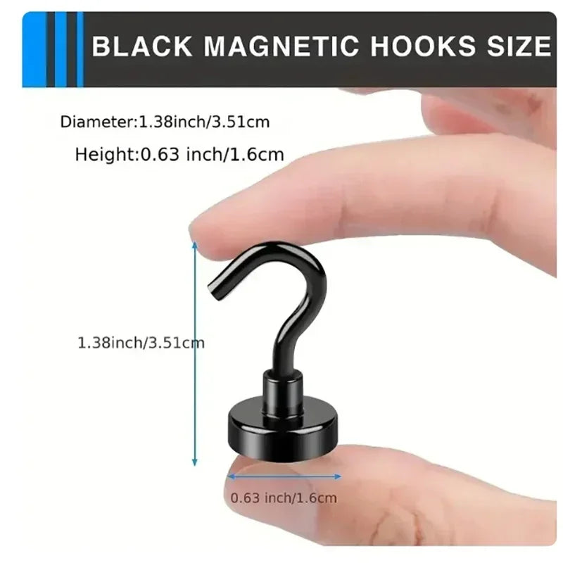 A close-up of a black magnetic hook showing its size relative to a human finger.