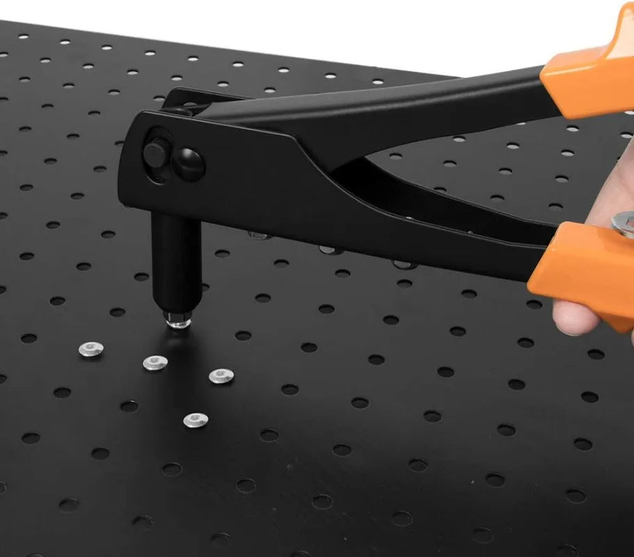 A hand holding a black and orange heavy duty hand rivet gun kit pressing a rivet into a dark surface.