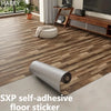 Roll of gray self-adhesive floor sticker placed on a wooden floor next to furniture.