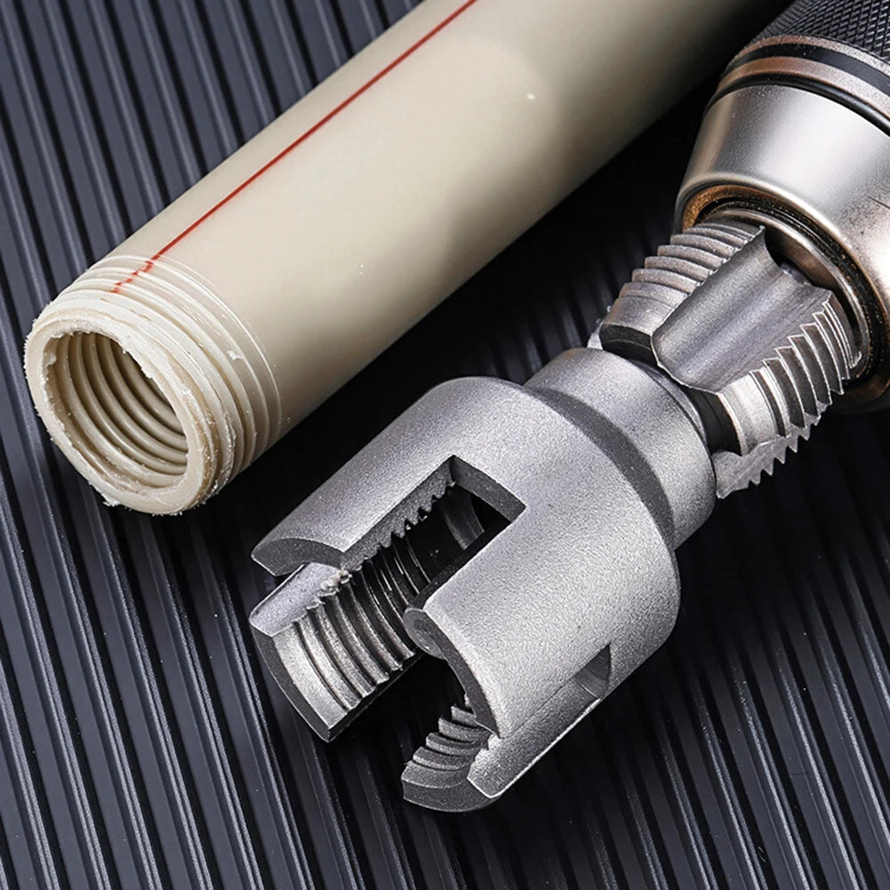 Close-up of an electric drill pipe thread cutting tool with a white and silver tube visible on a dark surface.