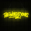 A neon yellow sign spelling out THE WORLD IS YOURS is suspended against a dark grid background.