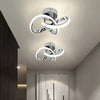 Modern LED ceiling light fixture with a silver finish and a white, swirling design mounted on a ceiling.