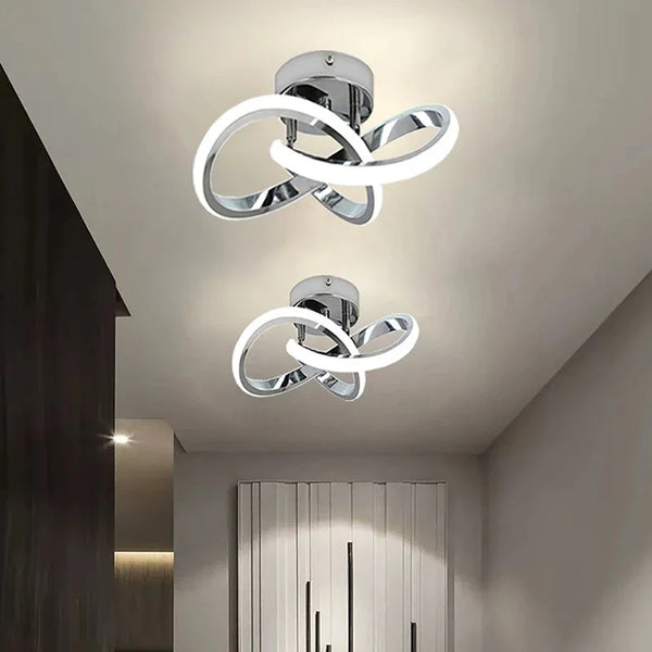 Modern LED ceiling light fixture with a silver finish and a white, swirling design mounted on a ceiling.