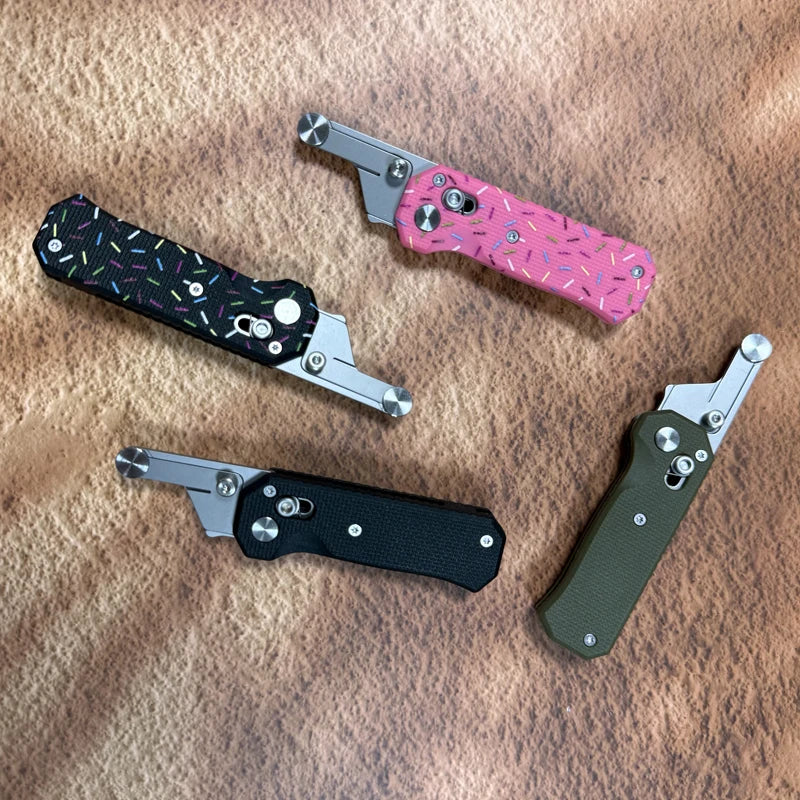 A collection of three folding utility knives featuring stainless steel blades and various colored handles on a brown leather 