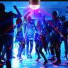 A performance featuring people illuminated by a bright, colorful disco ball light on a stage.