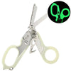A pair of tactical foldable shears with a green illuminated handle and silver blades.