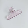 Klares Acryl-Federclip mit sichtbarer Metallfeder auf der Seite.