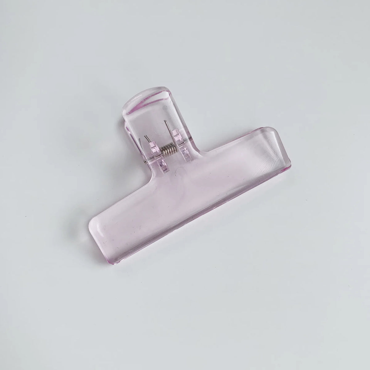 Klares Acryl-Federclip mit sichtbarer Metallfeder auf der Seite.
