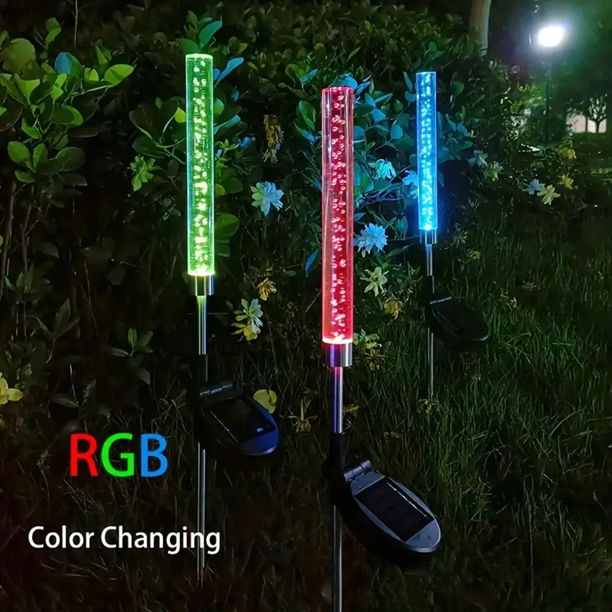 Drei vertikale Solar-LED-Lichter mit RGB-Farbwechsel, die eine grasbewachsene Landschaft beleuchten.