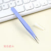 A pair of light blue precision crafting tweezers resting on a white keyboard.